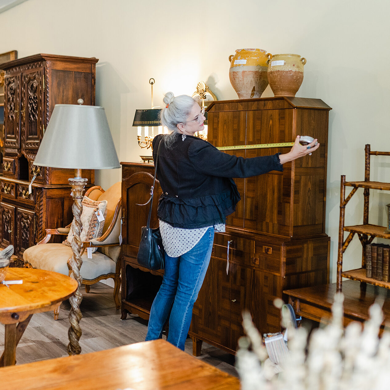 Interior designer sourcing and measuring vintage furnishings.